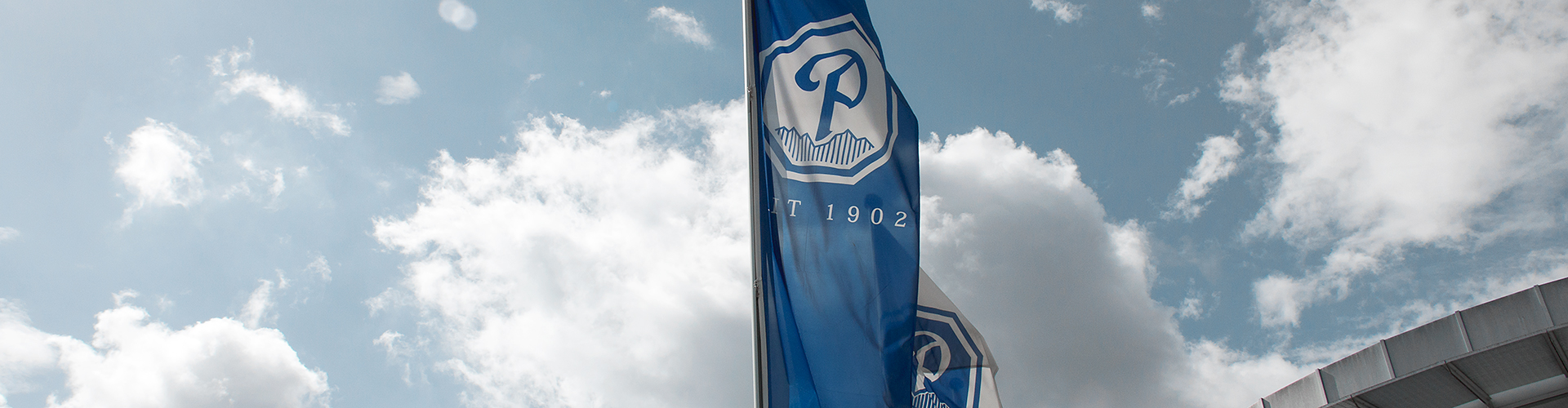 Pöschl-Fahnen im Wind vor dem Eingang zum Hauptgebäude auf dem Firmengelände