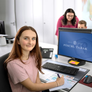 Auszubildende zur Industriekauffrau bei typischen Arbeiten an einem PC im Büro