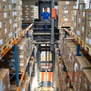 Fachkraft für Lagerlogistik bei Arbeit im Hubstapler im Hochregallager