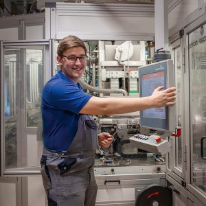 Mitarbeiter in Ausbildung zum Mechatroniker an einem Bedienpult